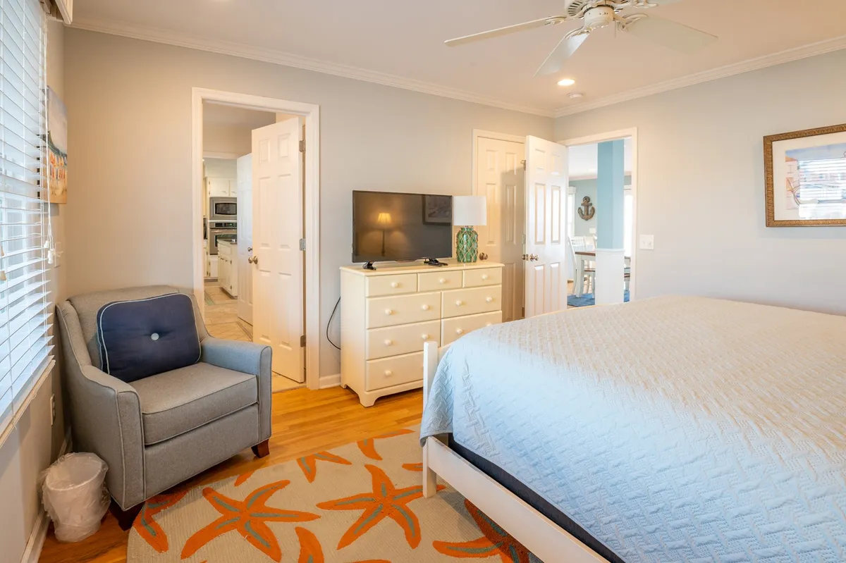 A cozy bedroom with a bed, armchair, television, and dresser—an ideal spot for relaxing, watching movies, or enjoying quiet moments. The setup suggests a private retreat within the home, perfect for movie nights or giving guests their own space.