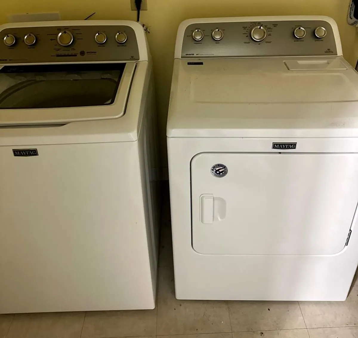 The image features a full-size washing machine and dryer in a practical laundry area. The machines are modern and well-maintained, emphasizing convenience and the ability to handle family-sized laundry needs during extended stays.