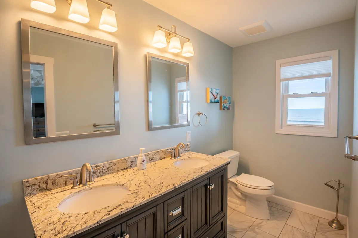A serene bathroom with a double sink vanity, large mirrors, and tasteful wall art—all designed for comfort and relaxation. The inviting mood and practical layout speak to the Jack and Jill bathrooms featured in the section.